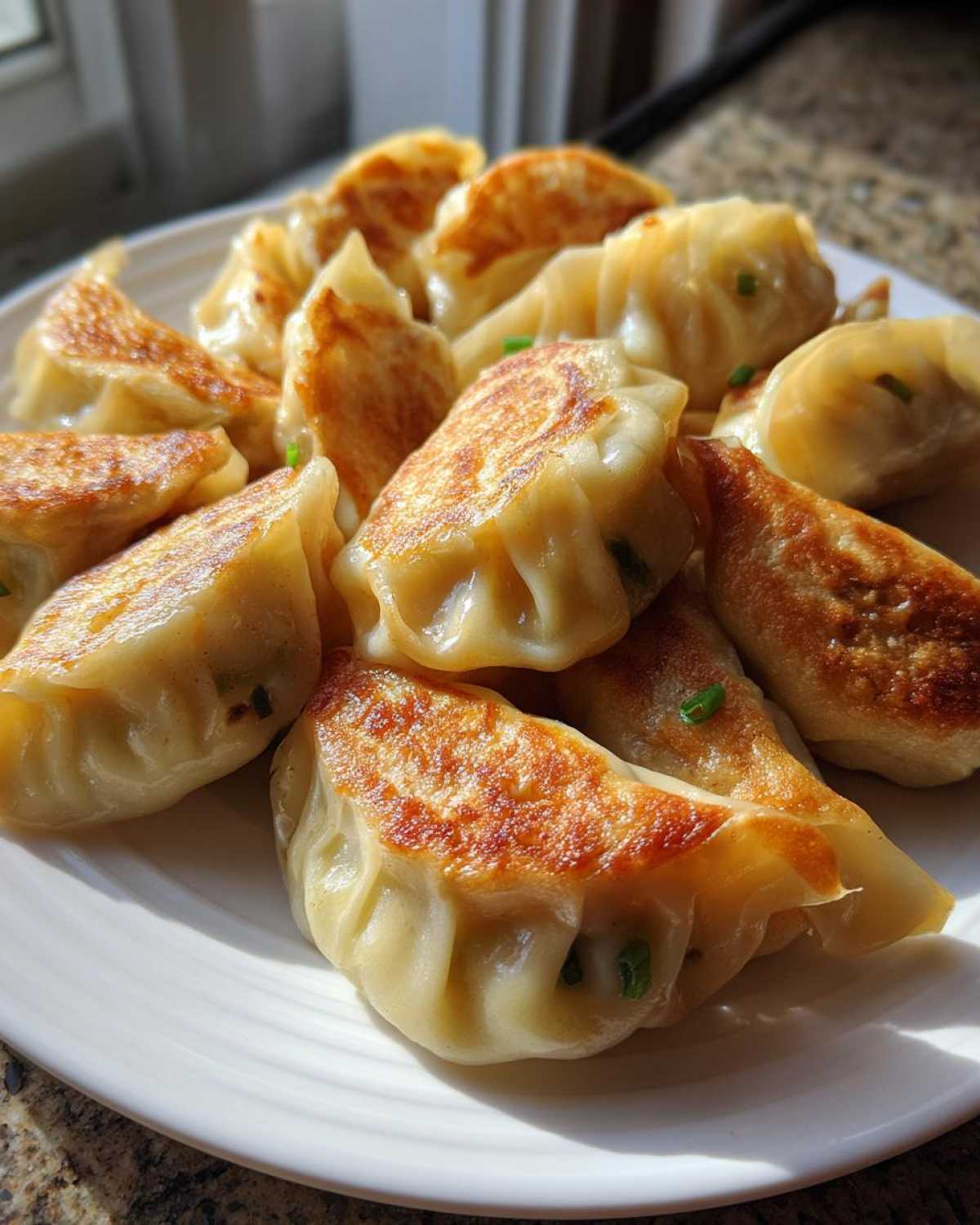 A plate piled high with perfectly pan-fried Traditional Chinese Dumplings, showing golden-brown crispy bottoms.