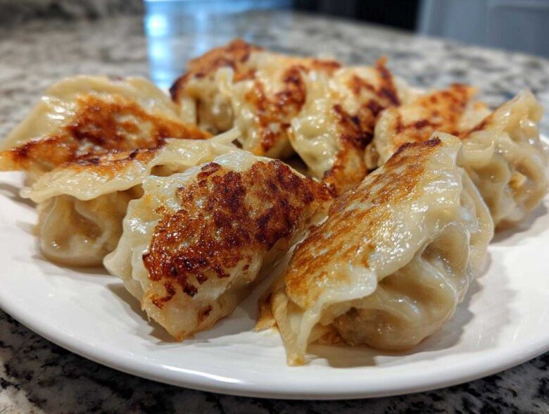 A plate of perfectly pan-fried Traditional Chinese Dumplings with golden-brown crispy bottoms.