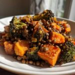 Close-up of a serving of veggie lentil salad featuring roasted sweet potatoes, dark green lentils, and charred broccoli florets.