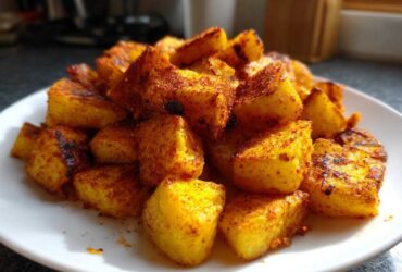 A mound of golden, crispy Air Fryer Crispy Breakfast Potatoes with Paprika piled high on a white plate.
