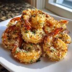A close-up of golden, crispy Air Fryer Crispy Garlic Parmesan Shrimp piled on a white plate, garnished with parsley.