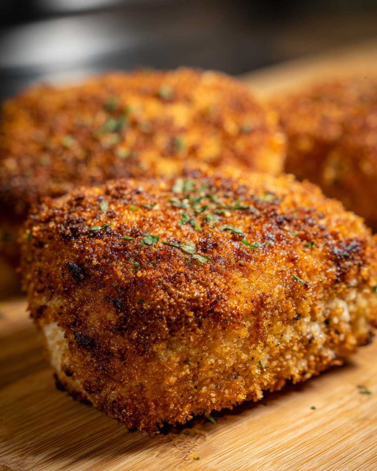 Close-up of golden brown, crispy Air Fryer Crispy Parmesan Chicken Cutlets garnished with parsley.