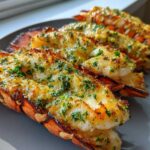 Close-up of three cooked Air Fryer Garlic Butter Lobster Tails, topped with melted butter and fresh parsley.