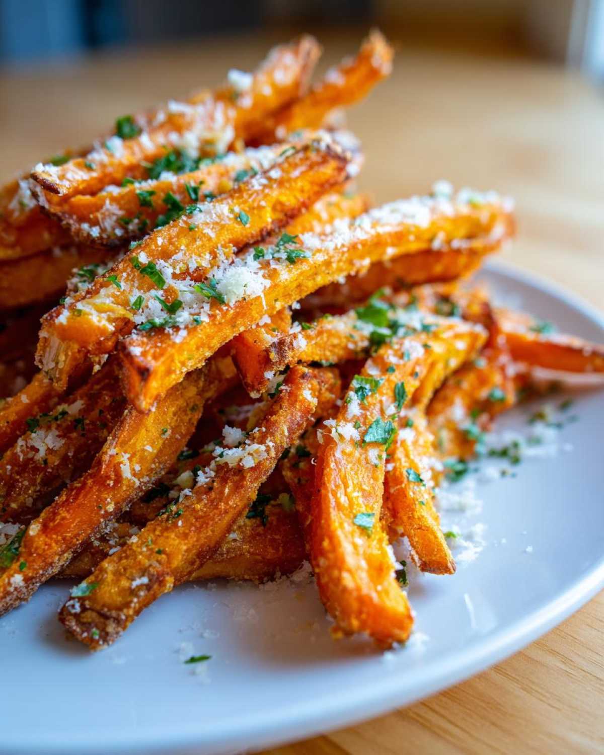 Close-up of crispy Air Fryer Garlic Parmesan Sweet Potato Fries topped with grated cheese and parsley.