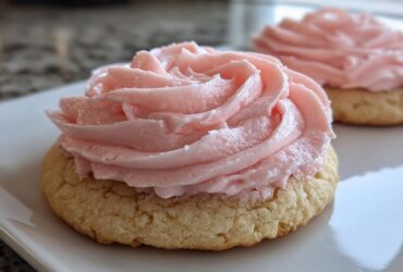 Close-up of a thick, soft Copycat Crumbl Sugar Cookie with Pink Frosting piped in a rose swirl.