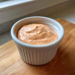 Close-up of creamy, orange-tinted Copycat Outback Bloomin' Onion Sauce in a white ramekin.