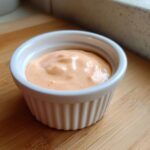 Close-up of creamy, orange-hued Copycat Outback Bloomin' Onion Sauce in a white ramekin.