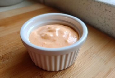 Close-up of creamy, orange-hued Copycat Outback Bloomin' Onion Sauce in a white ramekin.