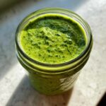 Close-up overhead view of vibrant green Copycat Panera Green Goddess Dressing stored in a glass mason jar.