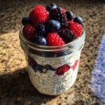 Close-up of Easy Berry Chia Overnight Oats topped with fresh raspberries, blueberries, and blackberries in a glass jar.