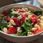 Close-up of Easy Strawberry Spinach Pasta Salad with Feta featuring shell pasta, bright red strawberries, and green spinach.