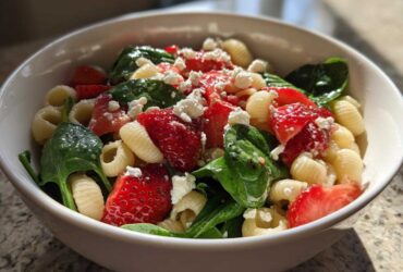 Close-up of Easy Strawberry Spinach Pasta Salad with Feta featuring shell pasta, bright red strawberries, and green spinach.