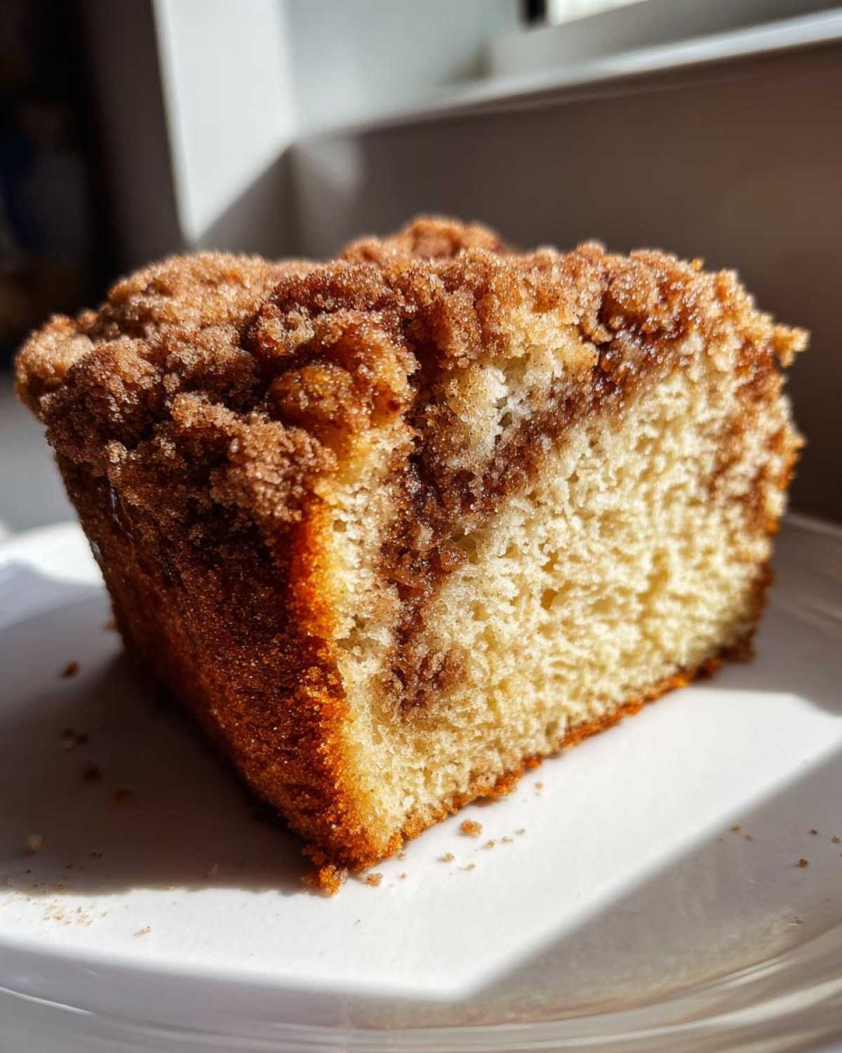 A close-up of a moist slice of Gluten-Free Cinnamon Sugar Coffee Cake featuring a thick, crumbly cinnamon streusel topping.