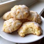 A stack of moist Gluten-Free Lemon Ricotta Cookies topped with a white lemon glaze, one cookie has a bite taken out.