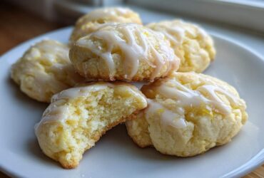 A stack of soft Gluten-Free Lemon Ricotta Cookies drizzled with white lemon icing, one cookie broken open to show the texture.