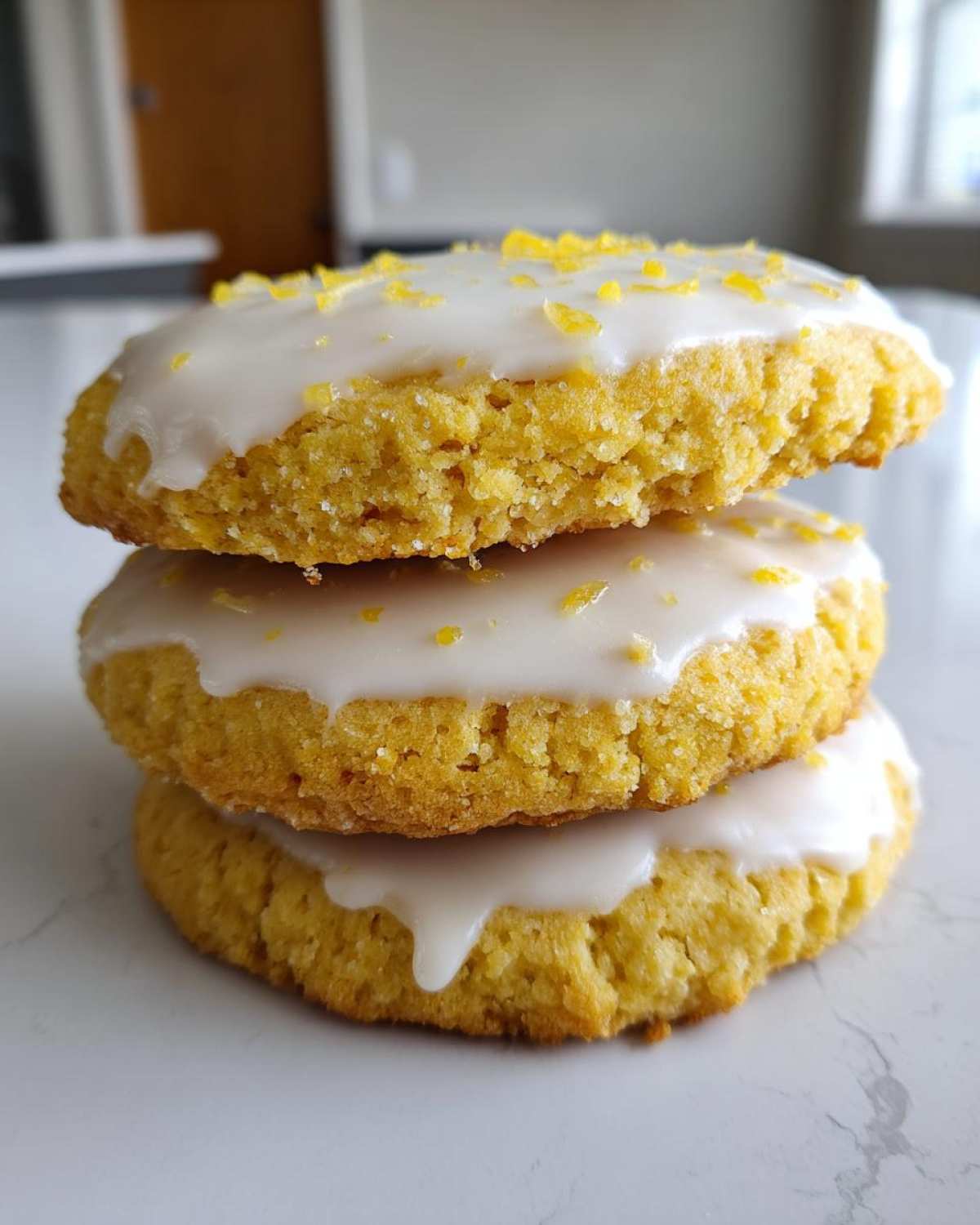 Three stacked Gluten-Free Lemon Sugar Cookies topped with white glaze and lemon zest.