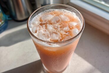 Close-up of a tall glass filled with an iced Copycat Starbucks Dragonfruit Refresher, showing condensation on the glass.