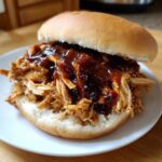 Close-up of a delicious Instant Pot BBQ Pulled Chicken Sandwich piled high on a soft bun with rich BBQ sauce.
