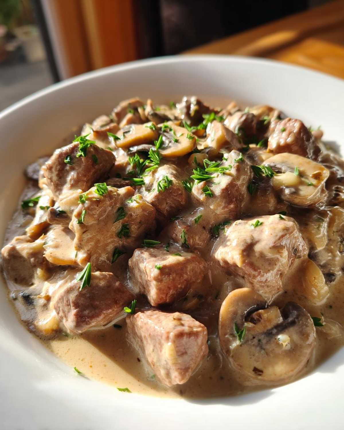 Close-up of tender beef cubes and sliced mushrooms coated in creamy sauce, garnished with parsley, ready to eat Instant Pot Beef Stroganoff with Mushrooms.