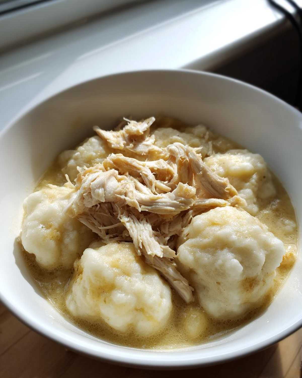 A close-up of fluffy dumplings and shredded chicken in broth, representing Instant Pot Chicken and Dumplings.