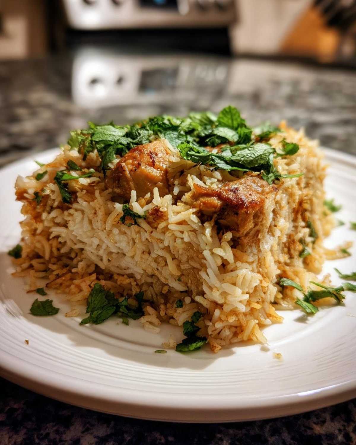 A mound of fluffy Instant Pot Chicken Biryani served on a white plate, topped with fresh mint.