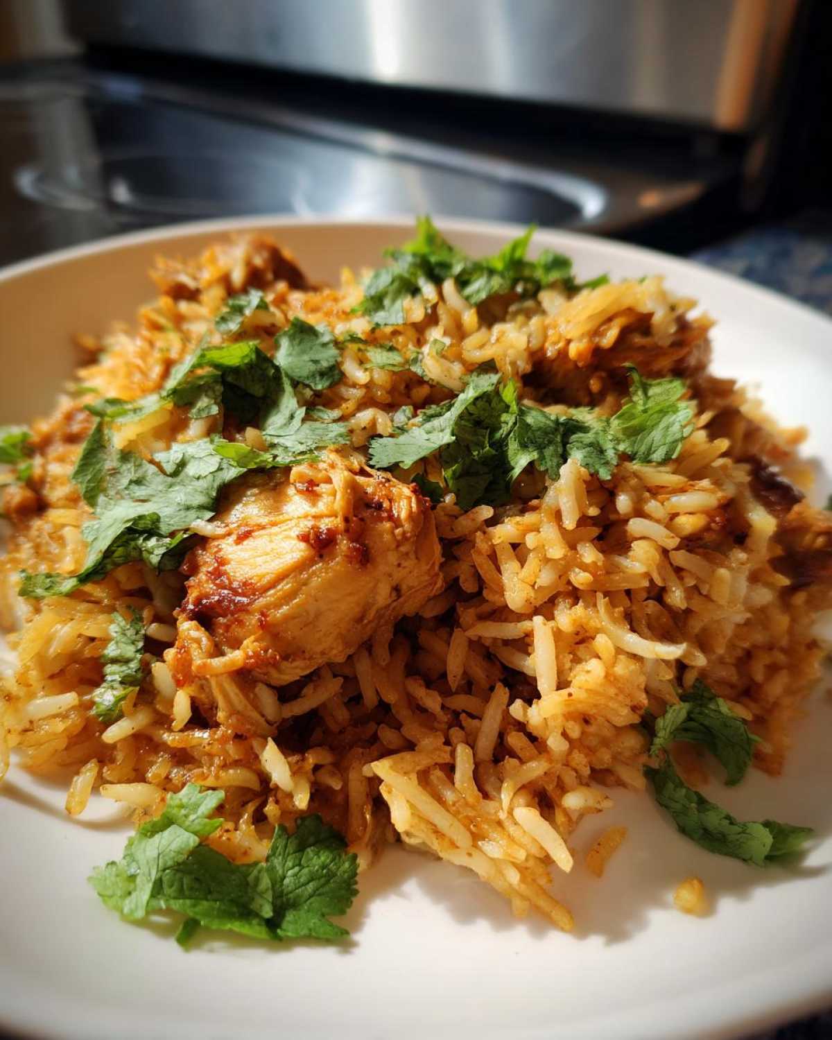 A close-up of a serving of flavorful Instant Pot Chicken Biryani, garnished generously with fresh green cilantro leaves.