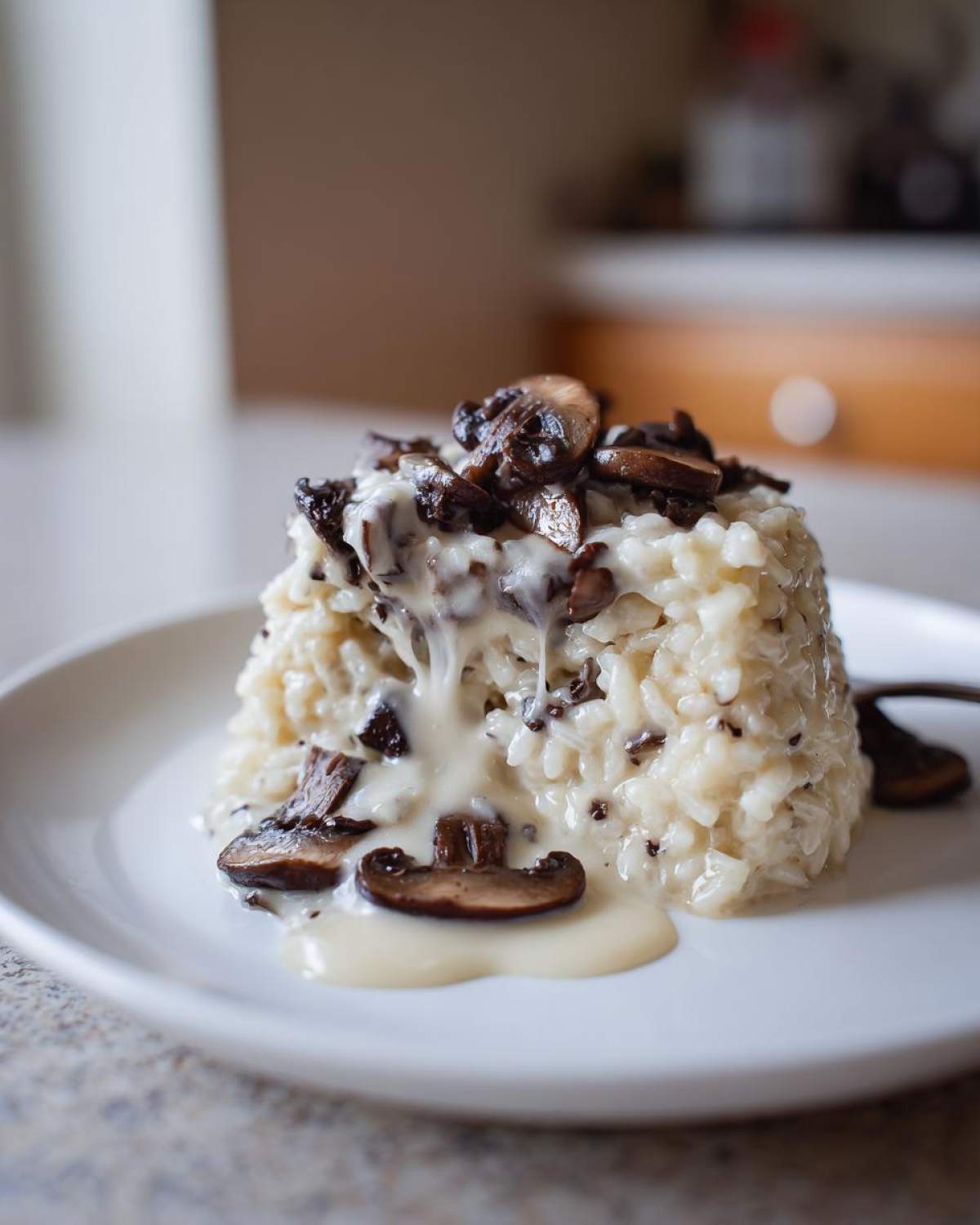 A perfectly molded serving of Instant Pot Creamy Mushroom Risotto topped with sautéed mushrooms and extra creamy sauce.