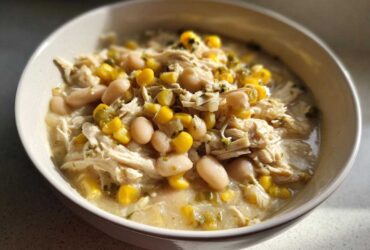 A close-up of a bowl filled with creamy Instant Pot White Chicken Chili with Corn, shredded chicken, and white beans.