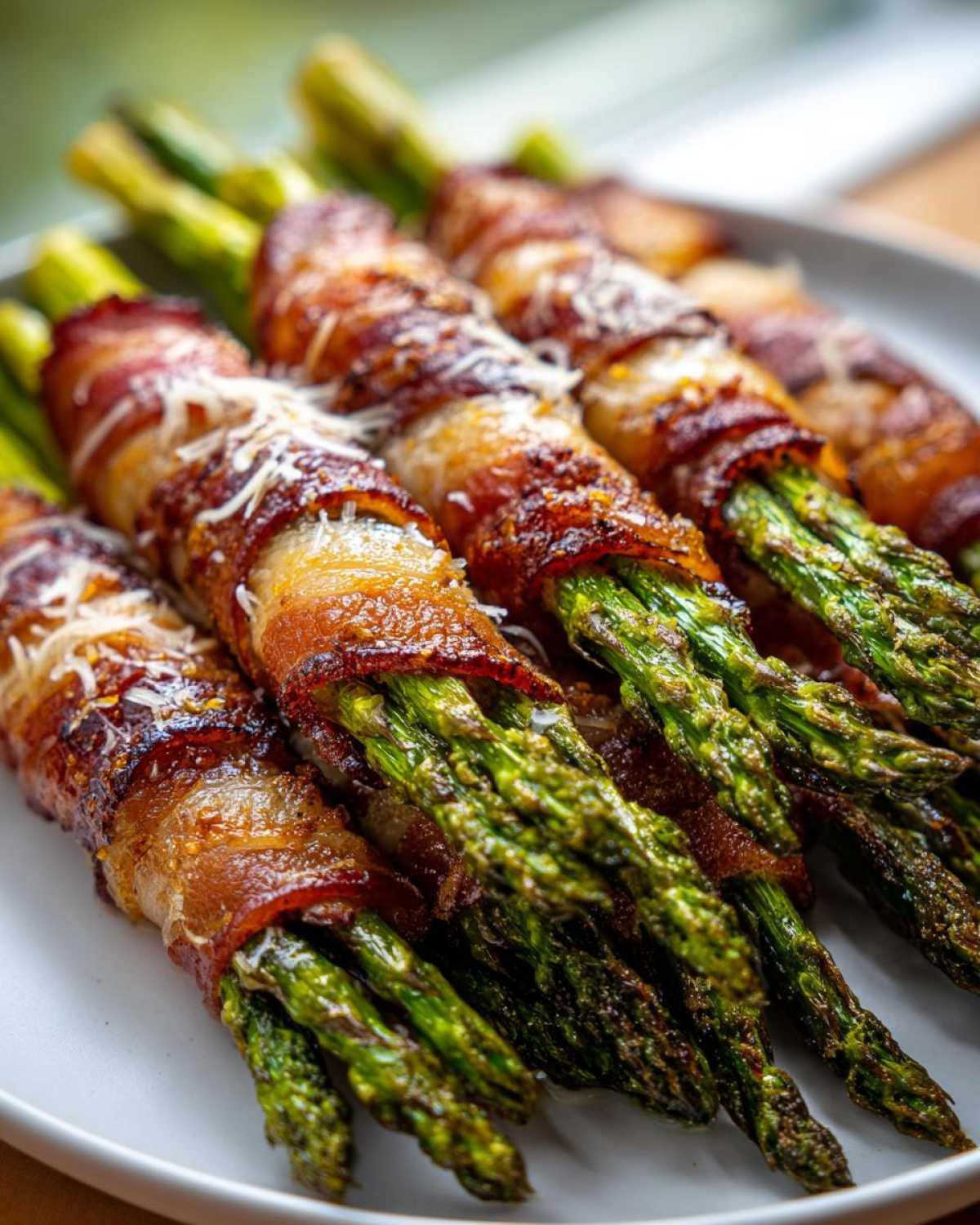 Close-up of perfectly cooked Keto Bacon Wrapped Asparagus Bundles, sprinkled with Parmesan cheese.