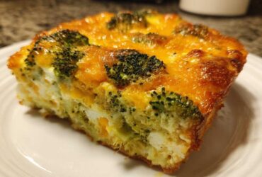 A close-up of a square slice of Keto Cheesy Broccoli Casserole with melted cheddar cheese topping.