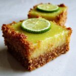 Two squares of No-Bake Coconut Lime Bars featuring a thick crust and bright green lime filling, topped with a lime slice.