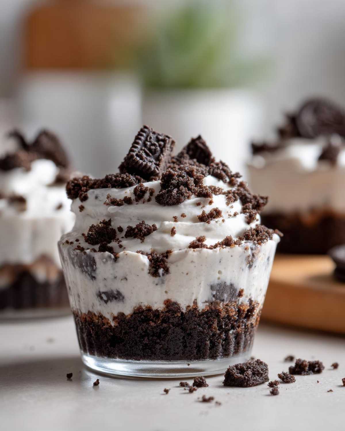 A close-up of a single serving of No-Bake Cookies and Cream Pie Cups topped with whipped cream and crushed cookies.
