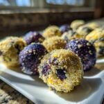 Close-up of several No-Bake Lemon Blueberry Energy Bites, some rolled in coconut and some showing vibrant blueberry color.