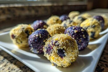 Close-up of several No-Bake Lemon Blueberry Energy Bites, some rolled in coconut and some showing vibrant blueberry color.