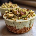 A close-up of a No-Bake Pistachio Cheesecake Cup with a graham cracker crust and topped generously with chopped pistachios.
