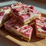 Close-up of stacked No-Bake Strawberry Cheesecake Bark squares with pink and white layers and freeze-dried strawberry topping.