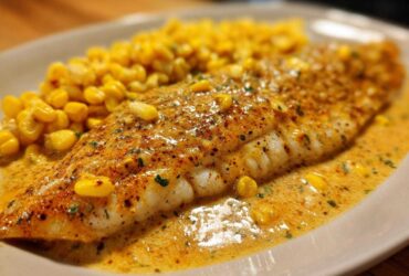 Close-up of a perfectly cooked fillet of One-Pan Creamy Cajun Catfish with Corn in a rich sauce.