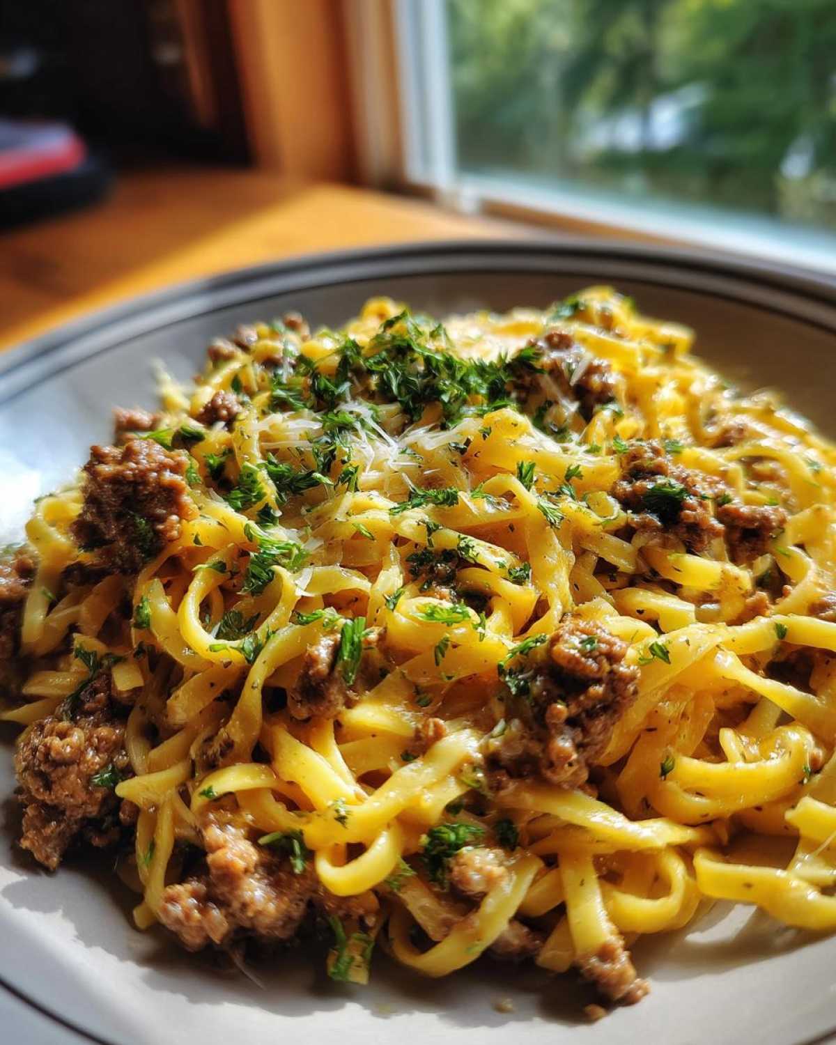 A close-up of a bowl of One-Pot Creamy Garlic Butter Beef and Noodles topped with parsley.