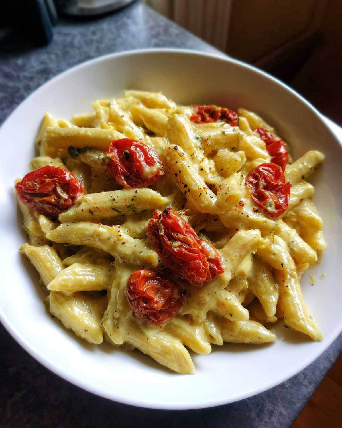 A close-up of One-Pot Creamy Goat Cheese Pasta with penne coated in rich sauce and topped with roasted cherry tomatoes.