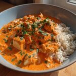 Close-up of One-Pot Creamy Tomato Basil Chicken and Rice served in a light blue bowl.