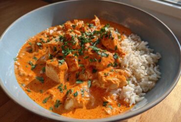 Close-up of One-Pot Creamy Tomato Basil Chicken and Rice served in a light blue bowl.