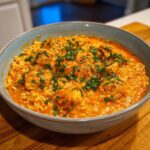A close-up of a bowl filled with One-Pot Creamy Tomato Basil Chicken and Rice, topped with fresh basil.