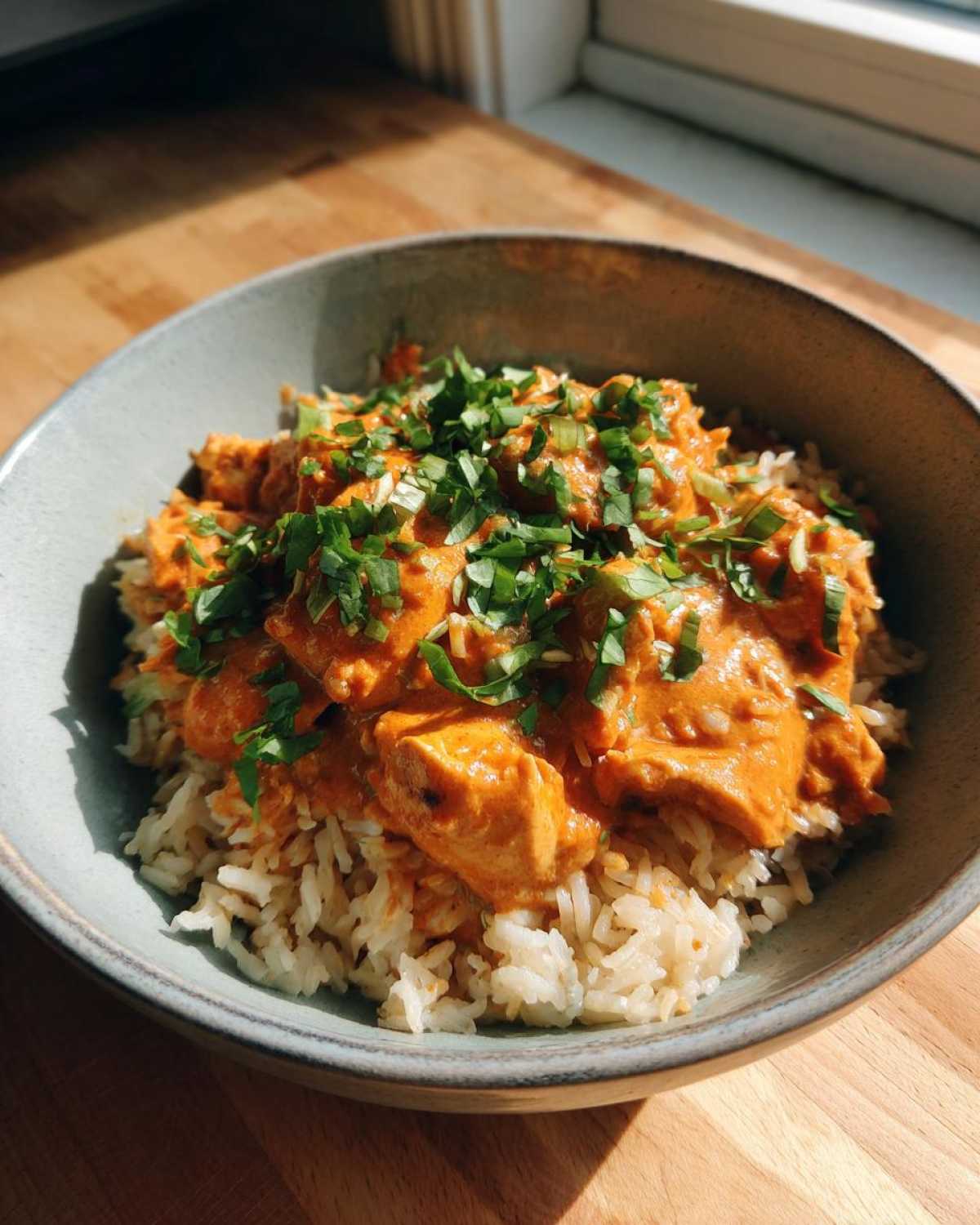 A bowl of One-Pot Creamy Tomato Basil Chicken and Rice topped with fresh chopped basil.