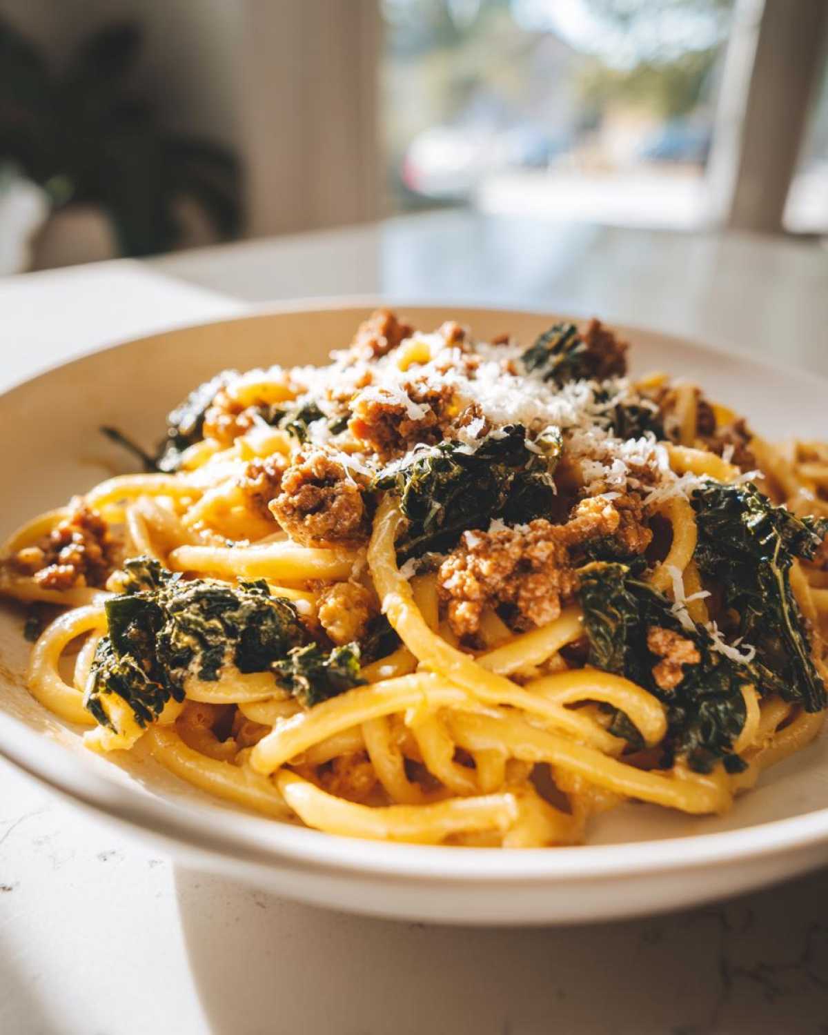 A close-up of a bowl of One-Pot Spicy Sausage and Kale Pasta topped with grated cheese.