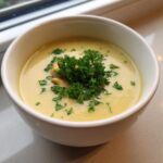 A close-up of Vegan Creamy Lemon Garlic White Bean Soup, garnished with fresh parsley and cashews.