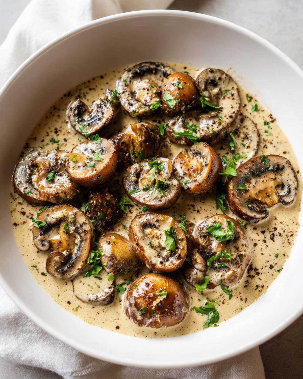 Close-up of sautéed mushrooms swimming in a rich, creamy mushroom sauce, garnished with parsley.
