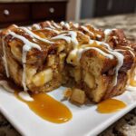 Close-up of a rich slice of apple bread pudding drizzled with caramel and vanilla icing.