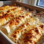 Close-up of freshly baked white chicken enchiladas covered in melted, bubbly, and browned cheese.