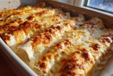 Close-up of freshly baked white chicken enchiladas covered in melted, bubbly, and browned cheese.