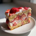 A perfect slice of homemade strawberry cake layered with vanilla sponge, whipped cream, and fresh strawberries.